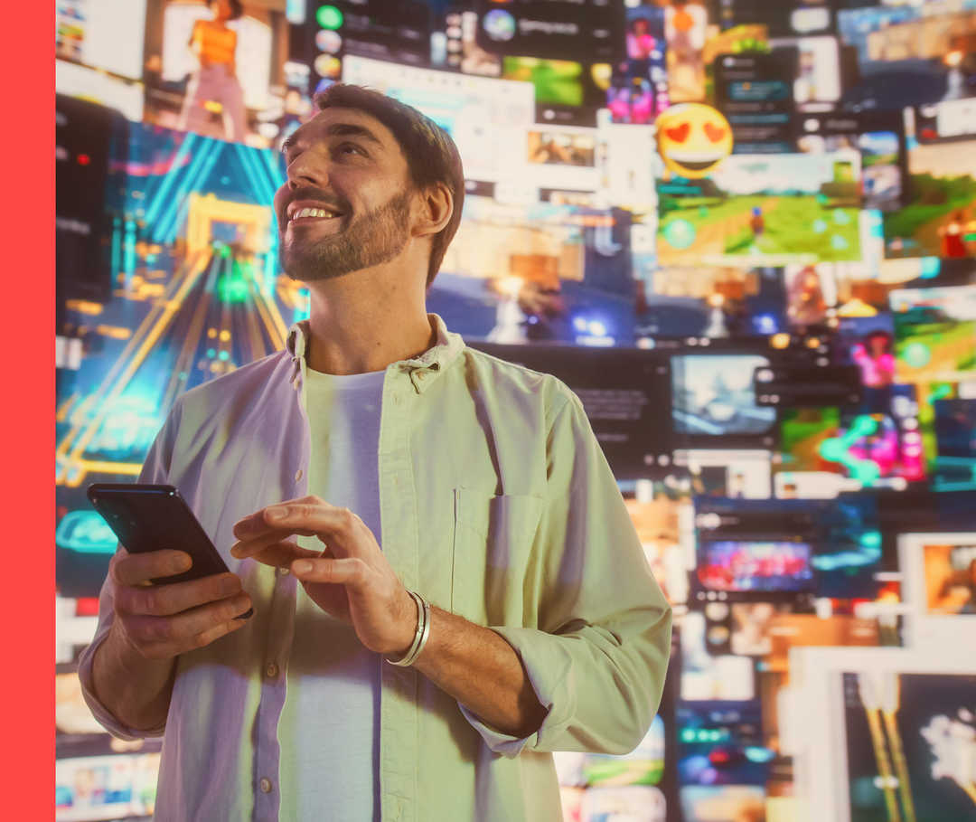 Ein Mann hält ein Handy in der Hand und schaut nach oben. Im Hintergrund sind viele verschiedene Bildschirme zu sehen.