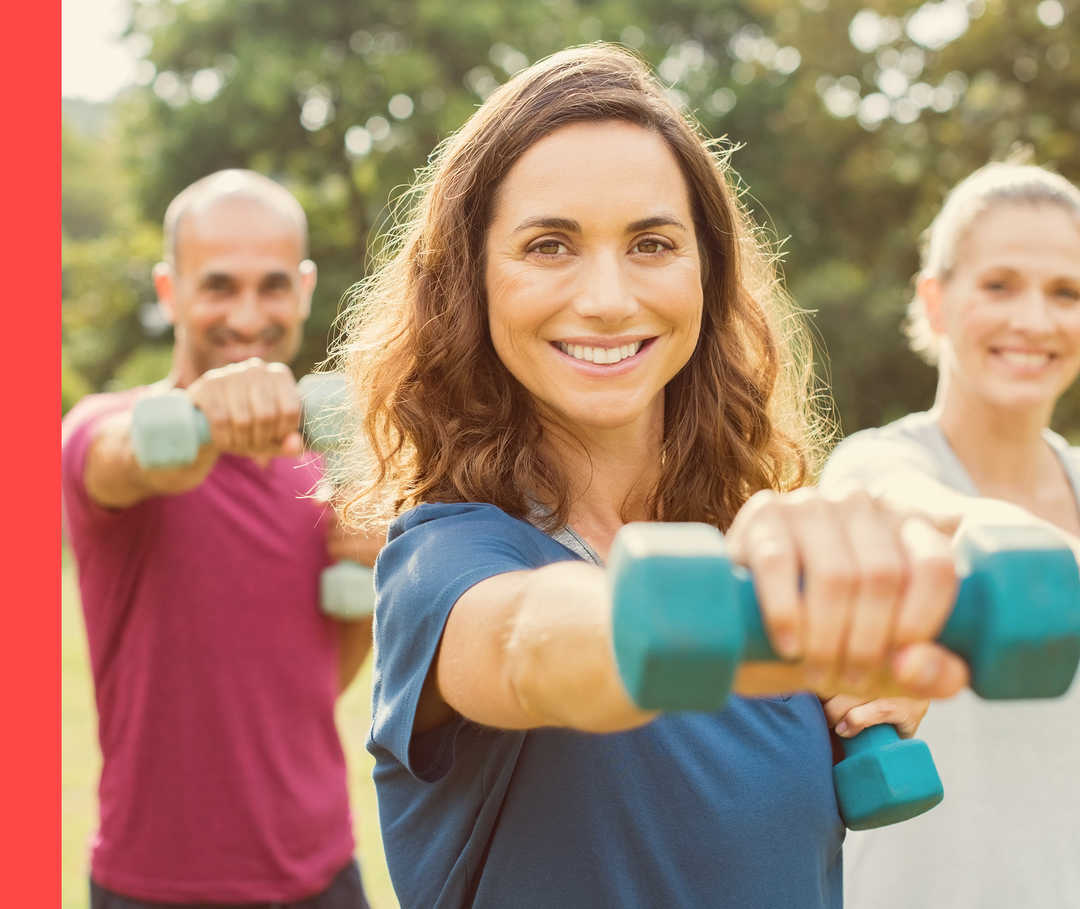 Zwei Frauen und zwei Männer trainieren mit Hanteln im Freien.