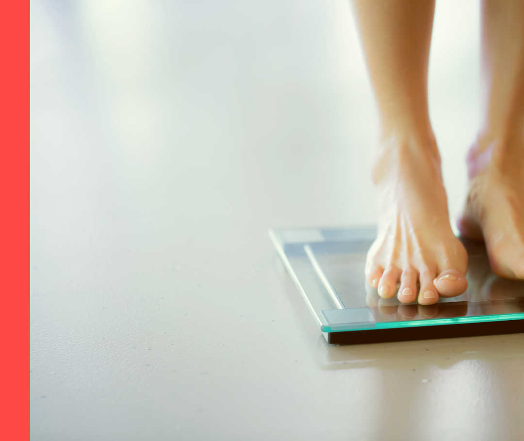 Eine Person steht auf der Waage. Man sieht nur die nackten Füße und die Waage.