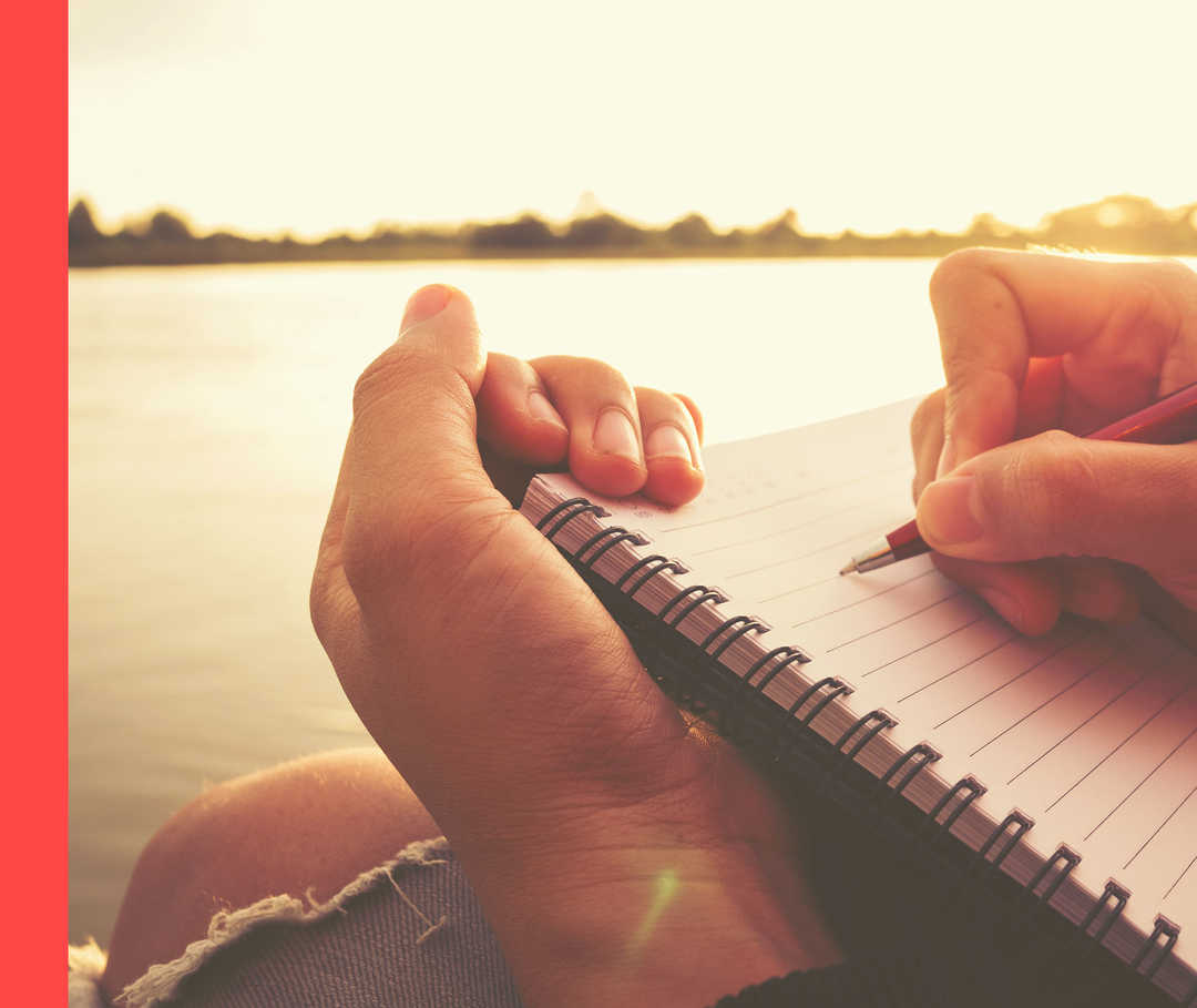 Ein Schreibblock mit einer Hand und einem Stift darauf.