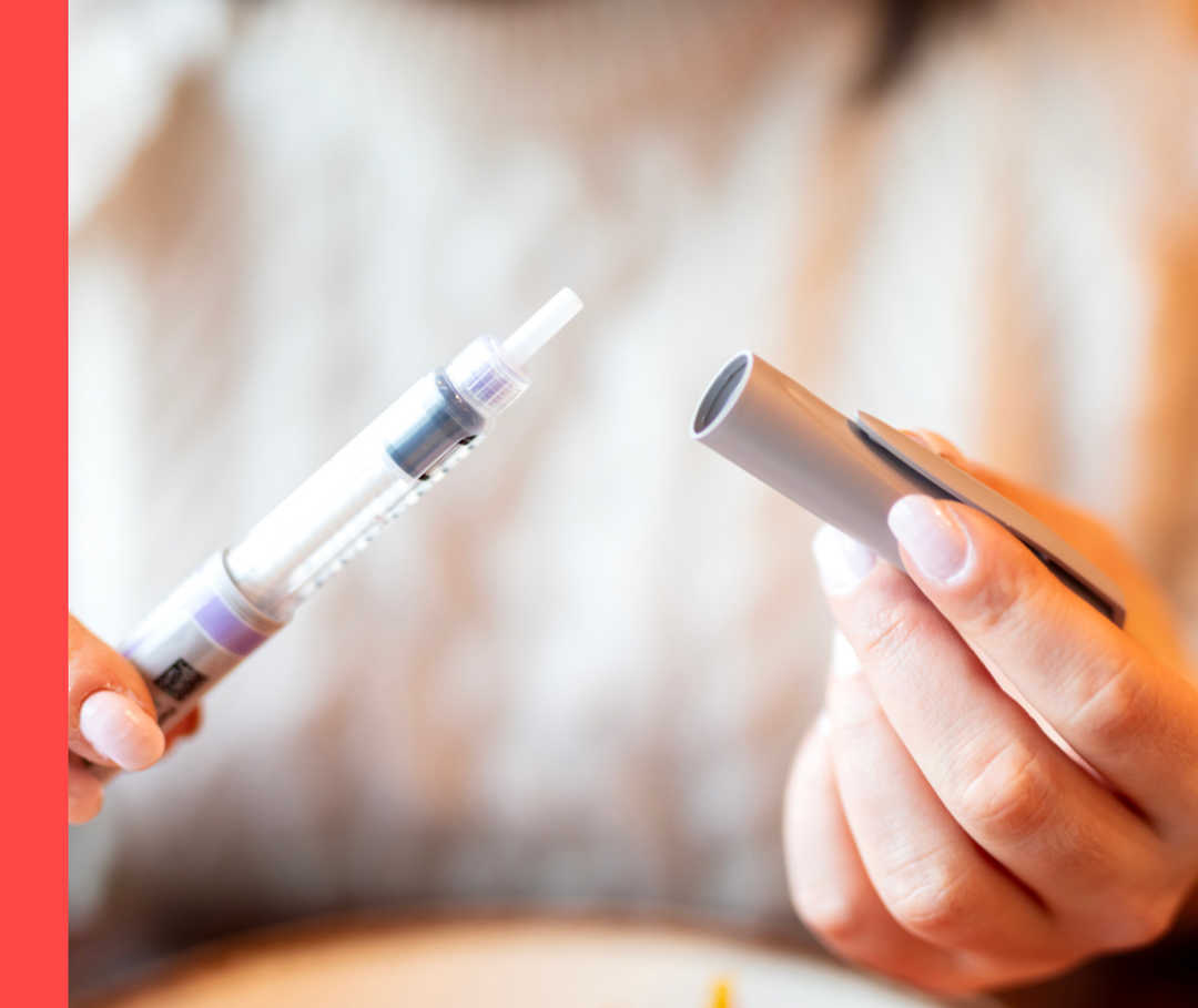 Eine Person zieht die Kappe eines Injektionspens ab.